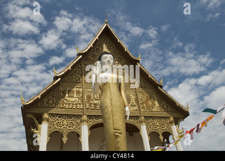 Una grande statua del Buddha sorge al di fuori di un tempio in Pha That Luang Stupa complesso in Viantiene, Laos Foto Stock