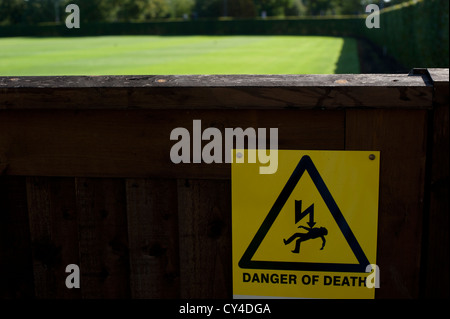 Segno su un cancello in legno per avvertimento pericolo di morte in entrata a un prato verde Foto Stock