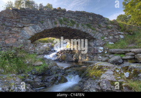 Vista di retromarcia del bellissimo ponte Ashness vicino Derwentwater Cumbria pittoresco ponte Packhorse con vista montagna Foto Stock