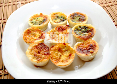 Mini Quiche su una piastra bianca - formaggio e spinaci Foto Stock