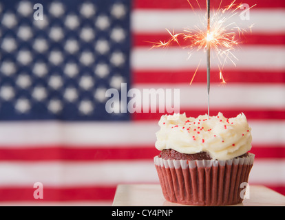 Studio shot di sparkler in cima tortina, bandiera americana in background Foto Stock