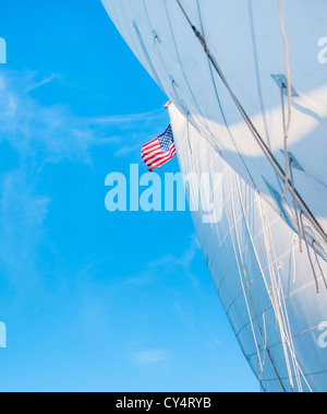 Stati Uniti d'America, Maine, Camden, vele bianche e bandiera americana contro il cielo blu Foto Stock