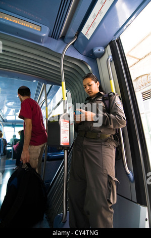 Un confine israeliano poliziotta utilizzando il suo telefono nel nuovo tram nel centro di Gerusalemme. Foto Stock