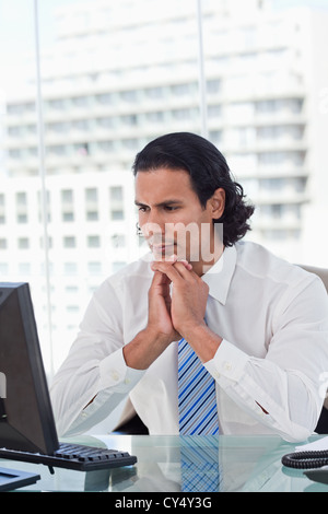 Ritratto di un uomo di affari di pensare mentre utilizzando un computer Foto Stock