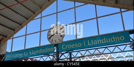 Orologio e multilingual benvenuto a Llandudno segno a questo centro città stazione ferroviaria a Conwy County Borough North Wales UK Foto Stock