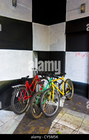 Tre moto colorati incatenato in una in bianco e nero dipinto di angolo di Nelson Street, Bristol. Foto Stock