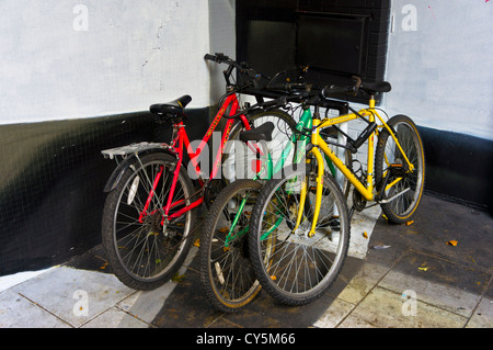 Tre moto colorati incatenato in una in bianco e nero dipinto di angolo di Nelson Street, Bristol. Foto Stock