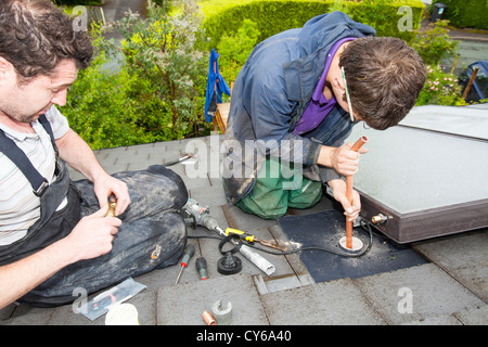 Workman solare montaggio pannelli termici per il riscaldamento di acqua e di un tetto di casa a Ambleside, Cumbria, Regno Unito Foto Stock