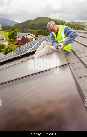 Solare pannelli fotovoltaici su un tetto di casa a Ambleside, Lake District, UK, con energia solare termica, acqua pannelli di riscaldamento. Foto Stock