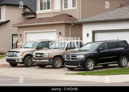 Una famiglia con tre enormi gas automobili guzzling in Fort McMurray il centro del tar sands industria. Foto Stock