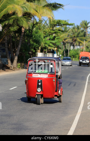 Red tuk tuk guidando lungo la principale strada costiera a Koggala in Sri Lanka. Foto Stock