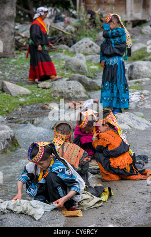 Kalash ragazze vestiti di lavaggio nella corrente che scorre attraverso il villaggio di Balanguru, Rumbur Valley, biglietto, Khyber-Pakhtunkhwa, Pakistan Foto Stock