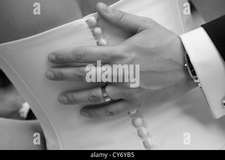 Giorno di nozze, sposo di toccare la mano sul retro delle spose abito, pulsanti sul retro dell abito da sposa in bianco e nero Foto Stock