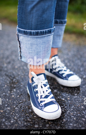In prossimità di un paio di sneakers blu e jeans blu su un terreno bagnato Foto Stock