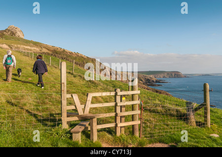 Una coppia di mezza età e il loro cane a piedi il South Devon strada costiera ad est di Plymouth in una serata estiva. REGNO UNITO Foto Stock