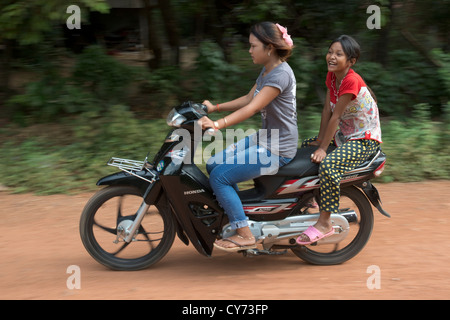 Due giovani ragazze passato velocità su una moto in O'Ambel village, Sisophon, Cambogia Foto Stock