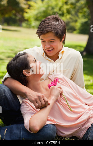 Donna che mantiene un fiore mentre giace contro il suo amico che sta guardando il suo Foto Stock