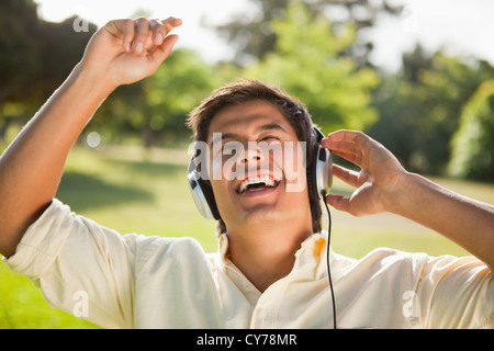 L'uomo solleva le braccia mentre utilizzando le cuffie per cantare insieme alla musica Foto Stock