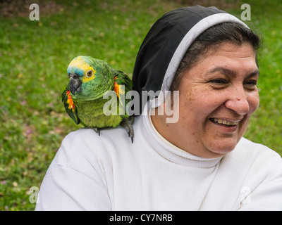 Una suora domenicana sorge sui terreni del Castillo de Carlota Palmerola, con un pappagallo sulla sua spalla in Areguá, Paraguay. Foto Stock