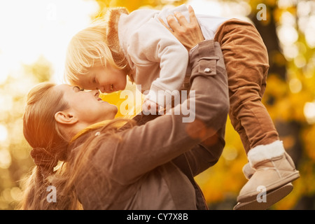 Giovane madre rising baby fino Foto Stock