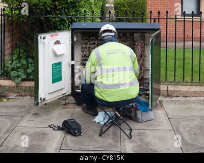 Un BT Openreach telecomunicazioni tecnico che lavora su un cabinet in banchina Foto Stock