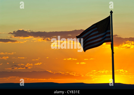 Tramonto dietro la bandiera americana sventolare nel vento vicino a Winslow, Arizona Foto Stock
