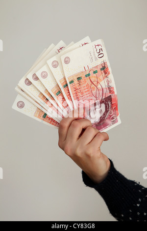 Una ragazza yound tenendo un mazzo di cinquanta pound note in Brighton, East Sussex, Regno Unito. Foto Stock