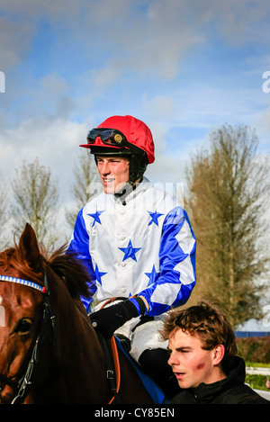 Cavallo e fantino essendo sfilavano intorno gli scommettitori a Wincanton racecourse Foto Stock