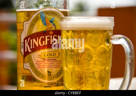 Orizzontale fino in prossimità di una fresca bottiglia di birra Kingfisher e un bicchiere pieno su un tavolo in India. Foto Stock