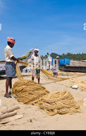 Ritratto verticale di pescatori mantenendo le loro reti sulla spiaggia di Kovalam, Kerala. Foto Stock