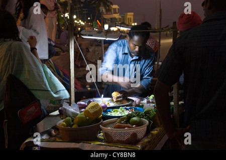 Ritratto orizzontale di una operosa uomo indiano la vendita di fast food da uno stallo sulla spiaggia di Kovalam. Foto Stock