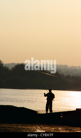 Silhouette del pescatore di pesca con sunrise in background Foto Stock