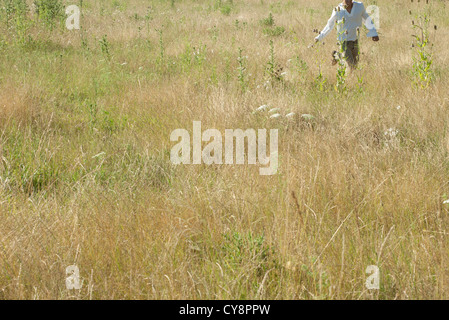 Uomo che corre attraverso il campo, metà sezione Foto Stock