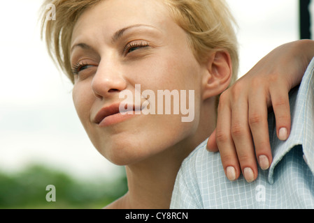 Giovane donna con la mano sull'uomo della spalla, guardando lontano e sorridente Foto Stock