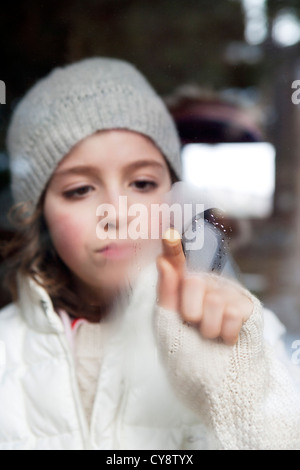 Ragazza disegno sul vetro appannato Foto Stock