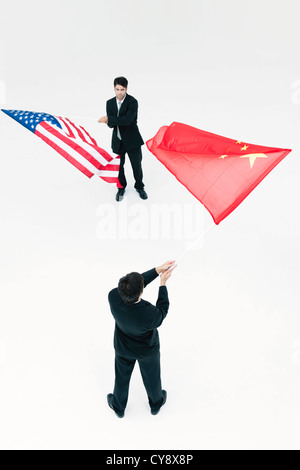 Gli uomini in piedi faccia a faccia, sventolando cinese e bandierine americane Foto Stock