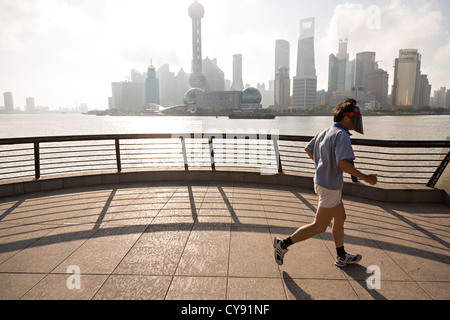 Un uomo fa avanzare la mattina presto sul Bund contro lo skyline della moderna Shanghai, Cina Foto Stock