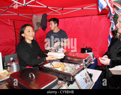 Sorridente donna asiatica serve cibo tailandese per un cliente a Durham City food festival, a nord-est dell' Inghilterra, UKfoo Foto Stock