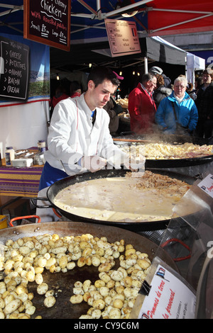 Uomo italiano servire patate arrosto e pollo cremoso Durham City food festival, North East England, Regno Unito Foto Stock