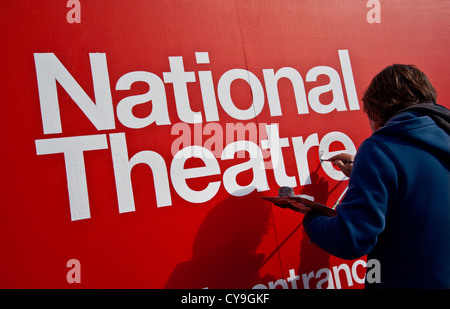 Segno scrittore mettendo i tocchi finali a dipinti a mano segno di ingresso al Teatro Nazionale SouthBank London REGNO UNITO Foto Stock