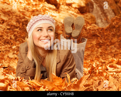 Immagine della bella donna allegra fissare sul suolo coperto secco fogliame autunnale, cute giovane lady divertirsi nel parco di caduta Foto Stock
