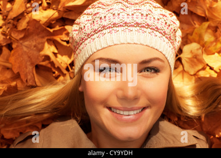 Foto di carino giovane donna recante sul terreno in autunno park, closeup ritratto di donna dolce su golden autunno sfondo Foto Stock