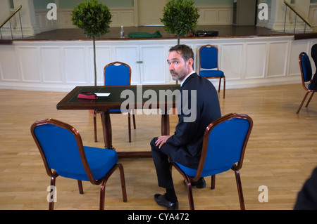 Un nervoso lo sposo attende per la sua cerimonia nuziale per avviare in un inglese town hall Foto Stock