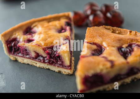 Due fette di ciliegia tart dessert shot dal di sopra su un ardesia naturale con superficie smaltata di ciliege in background. Foto Stock