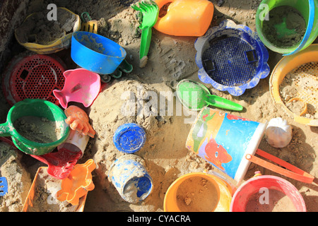 Buca di sabbia piena di giocattoli di plastica in colori luminosi Foto Stock