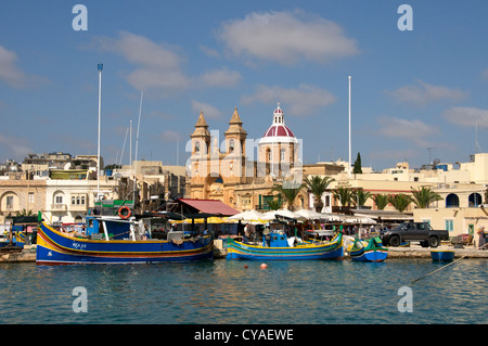 Le barche dei pescatori e la chiesa di Porto di Marsaxlokk Malta Foto Stock