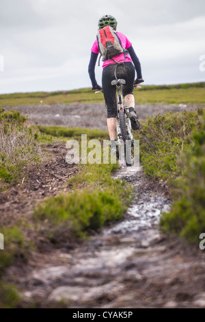 Una donna a cavallo lungo su una brughiera singola traccia in Northumberland. Foto Stock