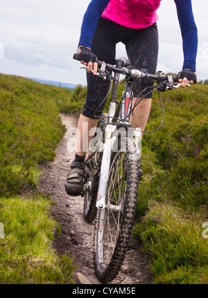 Un close-up di una donna in sella lungo su una brughiera singola traccia in Northumberland. Foto Stock