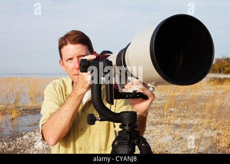 Fotografo professionista con un super teleobiettivo montato su di una sospensione cardanica di testa e treppiede. Foto Stock