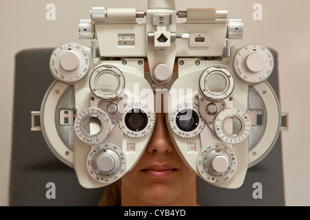 Donna paziente avente un occhio esame di prova su un Reichert ultramatic phoropter, autorefractometer strumento in clinica oculistica. Foto Stock
